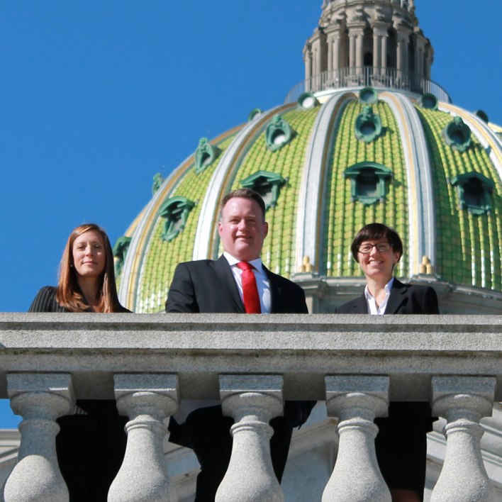 Three people standing in front of state capital building